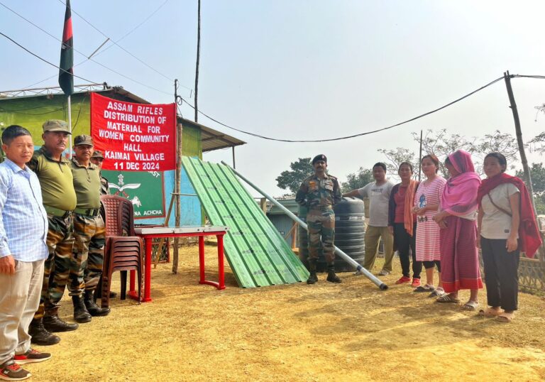 Assam Rifles personnel interacting with villagers during material distribution for a women's community hall in Kaimai Village.