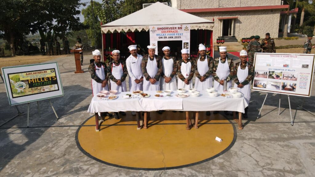 Participants in aprons and chef caps standing in front of a food table showcasing millet-based dishes during the cooking competition at Srikona Garrison.