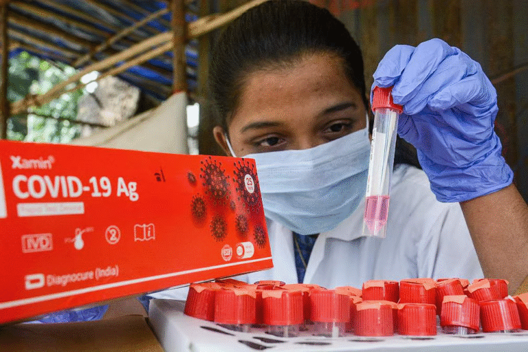 A healthcare worker in a face mask examines a COVID-19 antigen test sample at a testing center in India.
